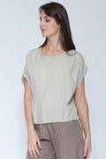 Woman wearing a beige top and brown pants against a white background