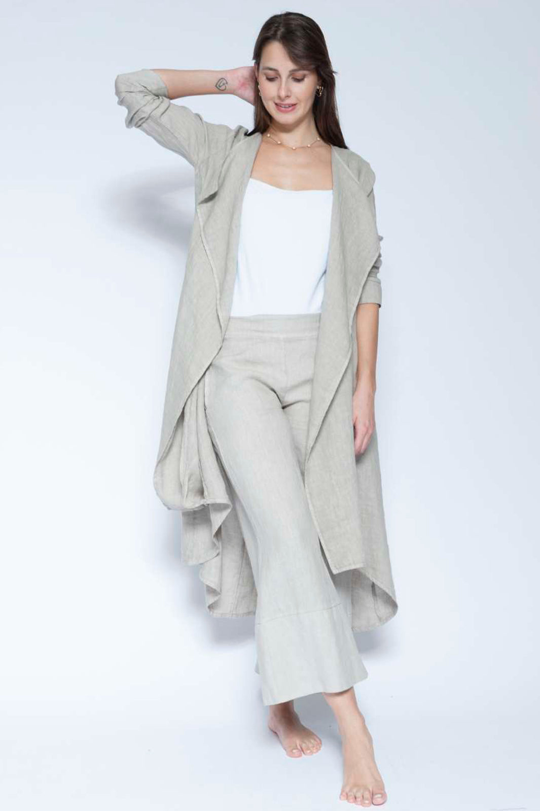 Woman wearing a light gray outfit with a white top on a plain background