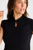 Woman wearing a black turtleneck shirt against a plain background