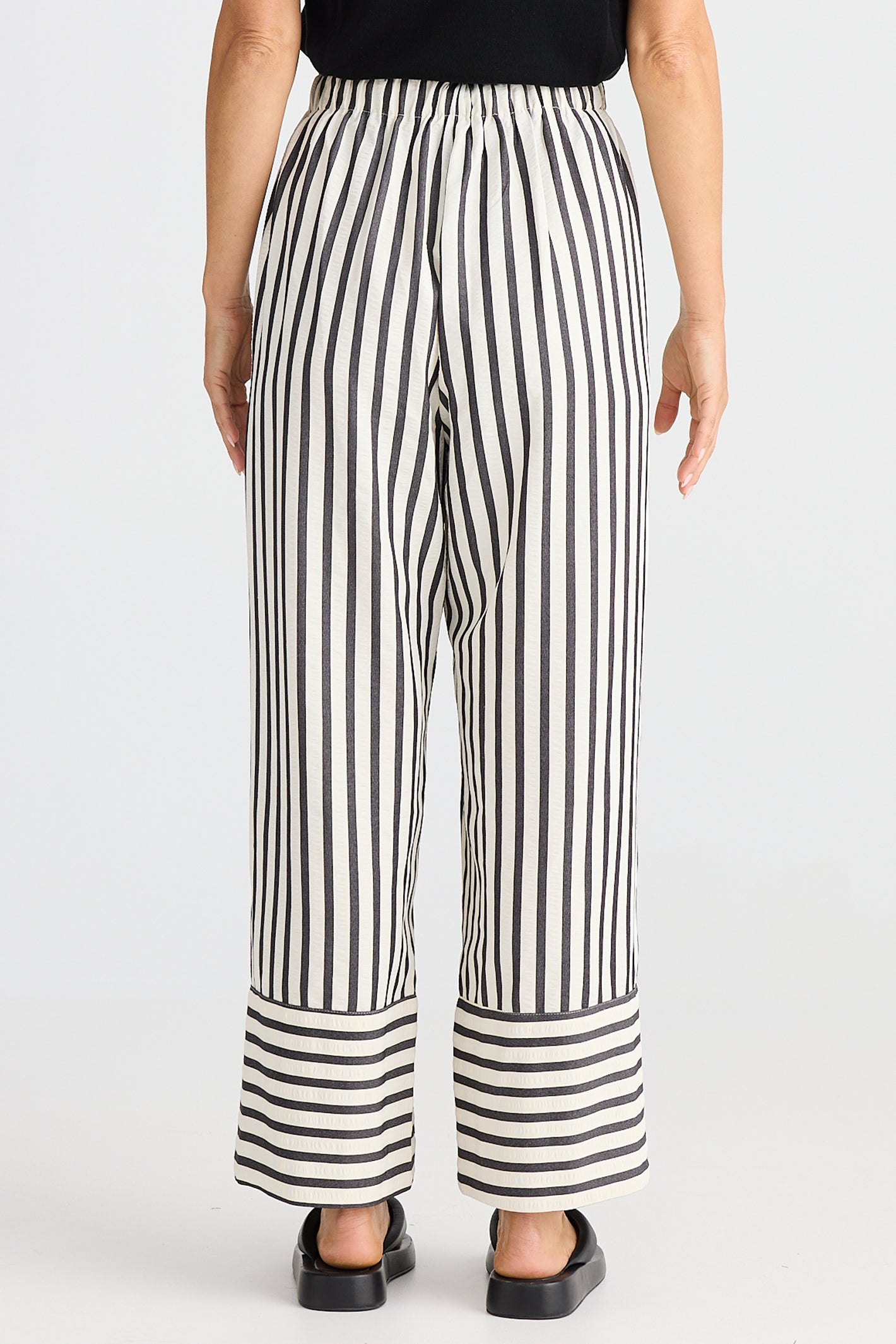 Black and white striped pants worn by a person on a white background