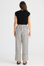 Woman wearing a black top and black and white striped pants on a white background