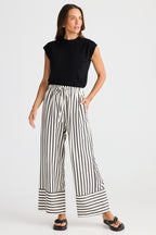 Woman wearing a black sleeveless top and striped pants on a white background