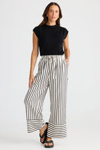 Woman wearing a black sleeveless top and wide-leg striped pants on a white background