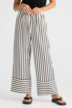 Person wearing black and white striped wide-leg pants on a plain background