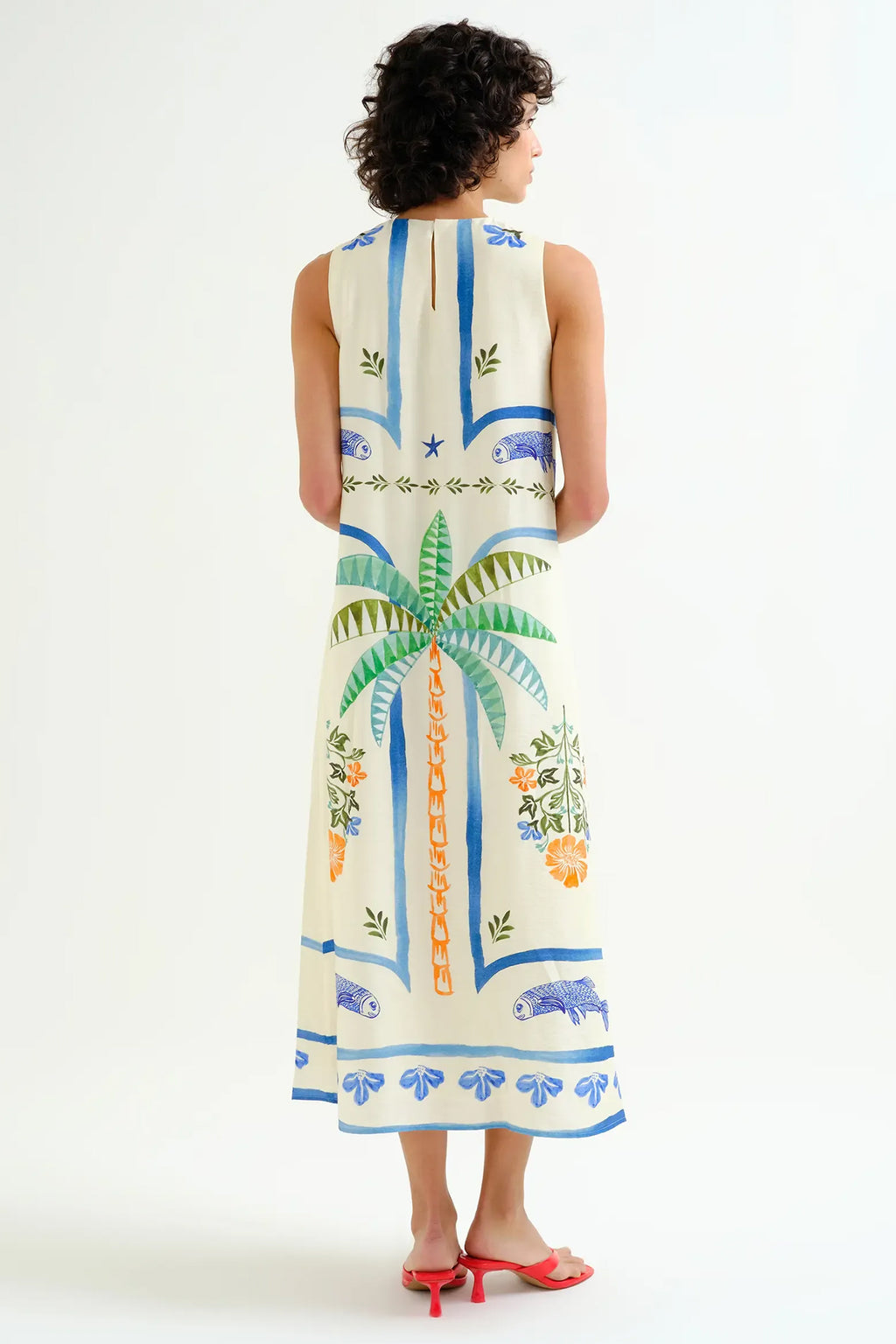 Woman wearing a sleeveless dress with a tropical pattern on a white background