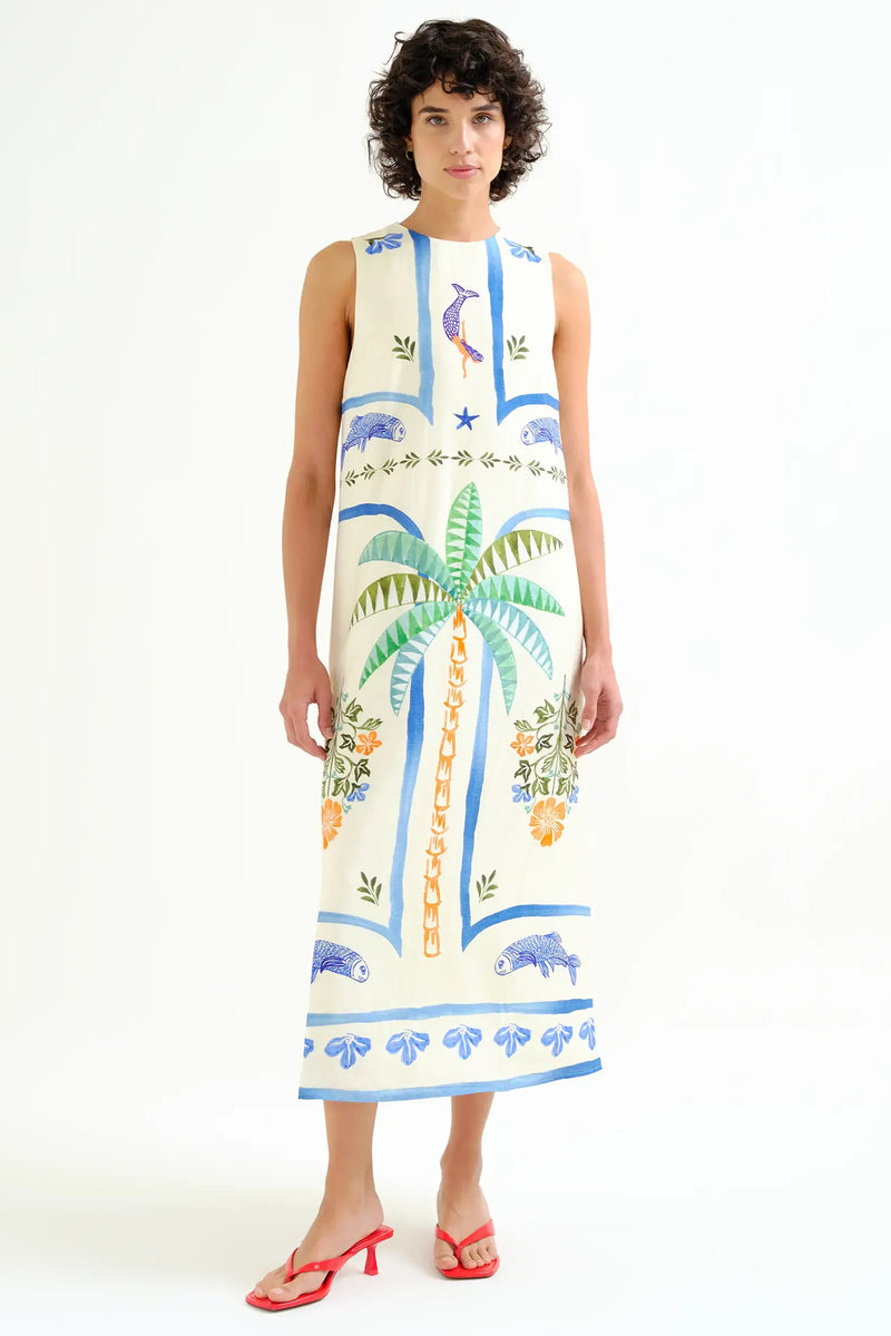 Woman wearing a sleeveless dress with tropical patterns on a white background