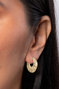 Gold hoop earring worn by a person with dark hair.