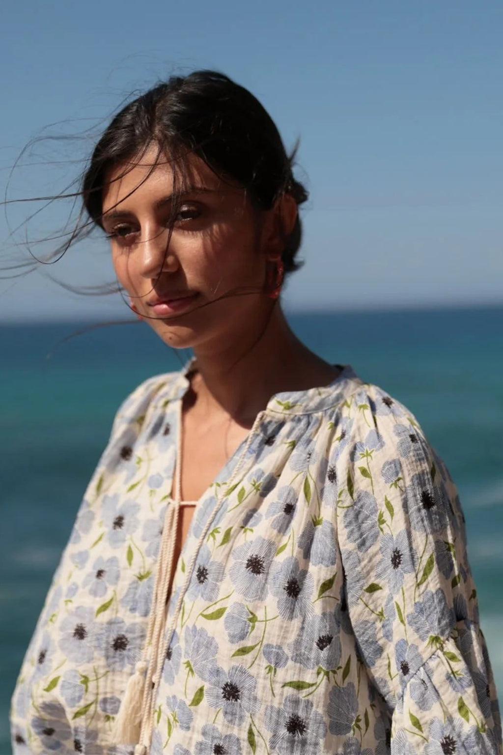 Woman wearing a floral dress with ocean and sky in the background