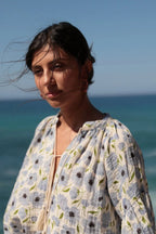 Woman wearing a floral dress with ocean and sky in the background