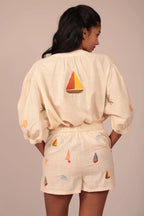 Person wearing a cream-colored outfit with sailboat patterns on a beige background