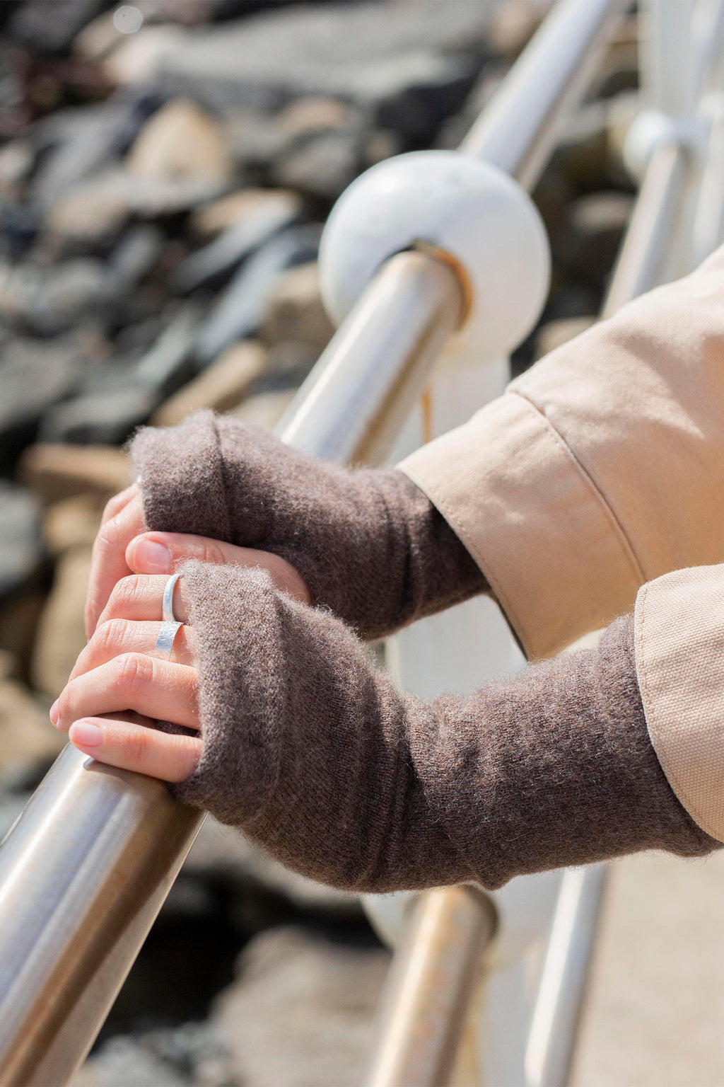 Turtle Doves Camel Brown Cashmere Fingerless Gloves, worn on hands holding a railing