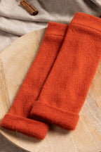 Turtle Doves Orange Cashmere Fingerless Gloves, pair on a wooden board