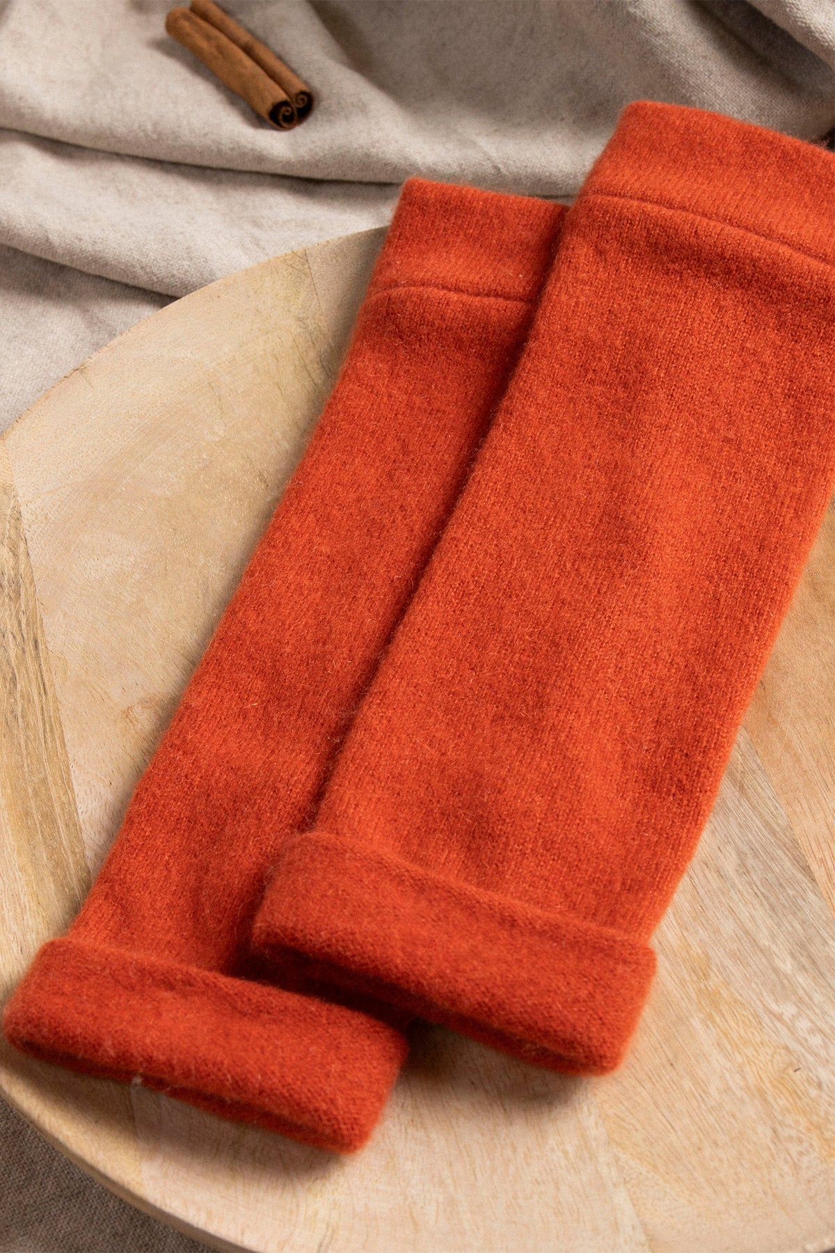 Turtle Doves Orange Cashmere Fingerless Gloves, pair on a wooden board
