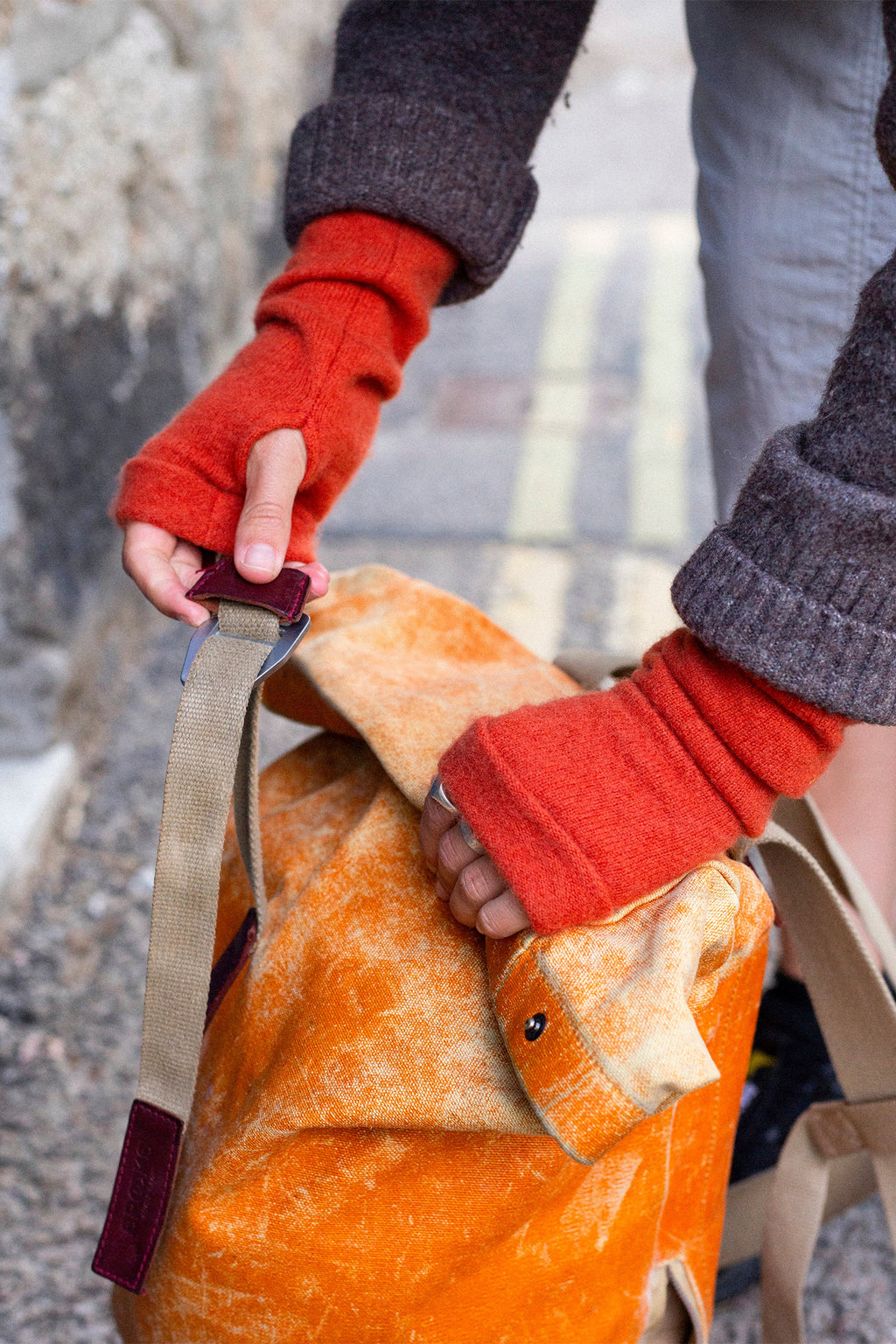 Turtle Doves Orange Cashmere Fingerless Gloves, worn outdoors carrying a bag